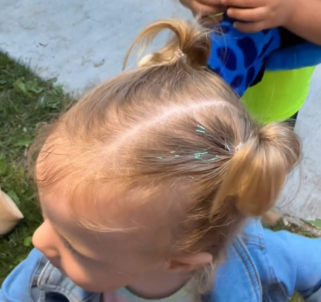 Photo showing little girl wearing Lily tinsel hair in her pigtails. Child is two years old, showing anyone, no matter the age can add this hair accessory to their hair.