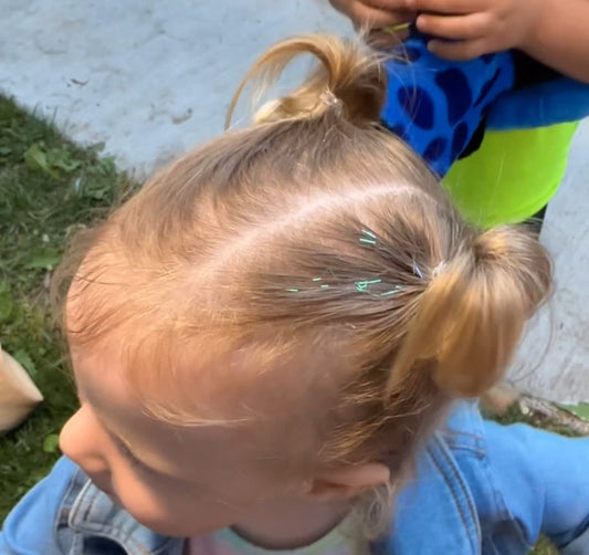 Photo showing little girl wearing Lily tinsel hair in her pigtails. Child is two years old, showing anyone, no matter the age can add this hair accessory to their hair.