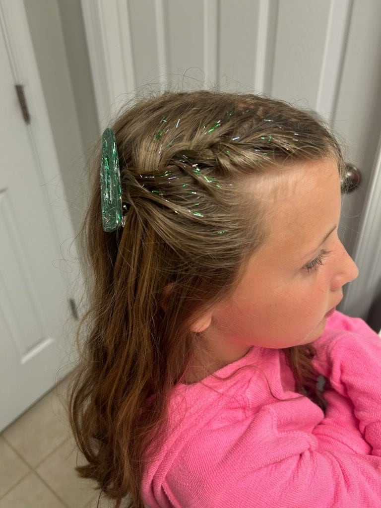 A little girl has green and silver tinsel hair gel in her braid. She is a Philadelphia Eagles fan and chose colors to support her favorite sports team.  She paired this with a WildMane tinsel hair resin clip for an extra special sparkly style.